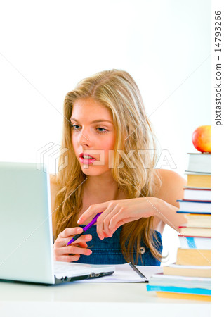Pensive young girl sitting at table with books and looking on laptop. Pensive young girl sitting at table with books and looking on laptop. 14793266