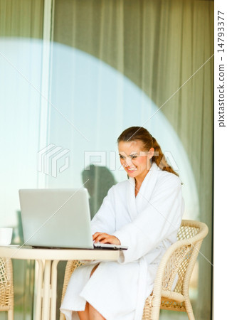 Smiling pretty woman in bathrobe sitting at table on terrace and Smiling pretty woman in bathrobe sitting at table on terrace and 14793377