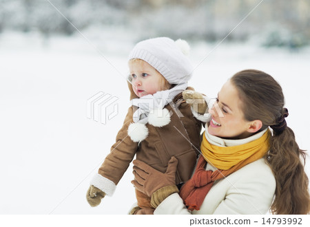 Happy mother and baby looking on copy space in winter outdoors Happy mother and baby looking on copy space in winter outdoors 14793992