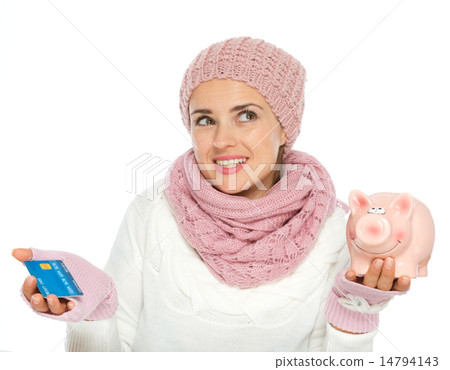 Confused woman in knit winter clothing holding credit card and p Confused woman in knit winter clothing holding credit card and p 14794143