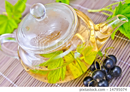 Tea with black currants in glass teapot on bamboo napkin Tea with black currants in glass teapot on bamboo napkin 14795074