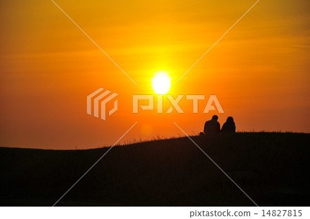 A couple sitting towards the sunset A couple sitting towards the sunset 14827815