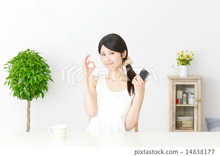 A woman holding a smartphone and giving an OK sign 14838177