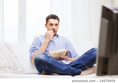 man watching tv and eating popcorn at home man watching tv and eating popcorn at home 14870959