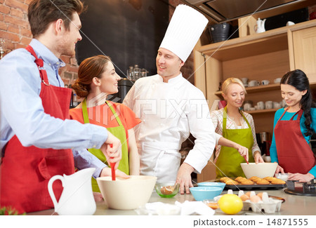 圖庫照片: happy friends and chef cook baking in kitchen