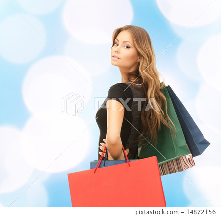 young woman with shopping bags over blue lights young woman with shopping bags over blue lights 14872156