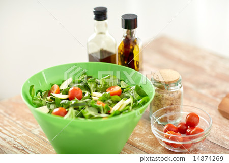 close up of salad bowl and spices on kitchen table close up of salad bowl and spices on kitchen table 14874269