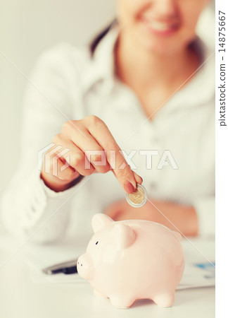 woman hand putting coin into small piggy bank 14875667