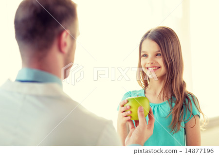 male doctor giving an apple to smiling little girl male doctor giving an apple to smiling little girl 14877196