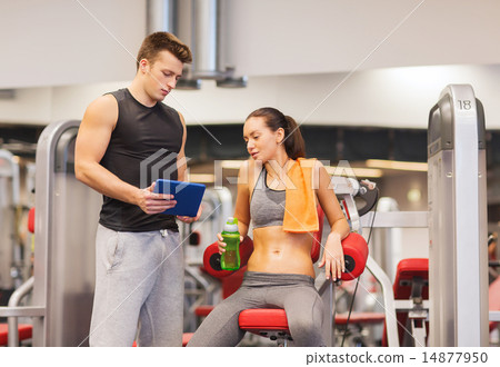 smiling young woman with personal trainer in gym smiling young woman with personal trainer in gym 14877950