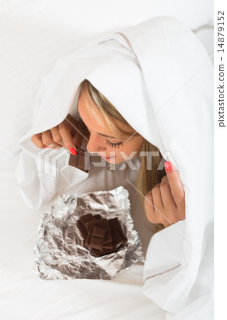 Woman eating chocolate in bed 14879152