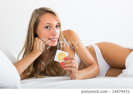 Sexy woman holding condom in bed Sexy woman holding condom in bed 14879431