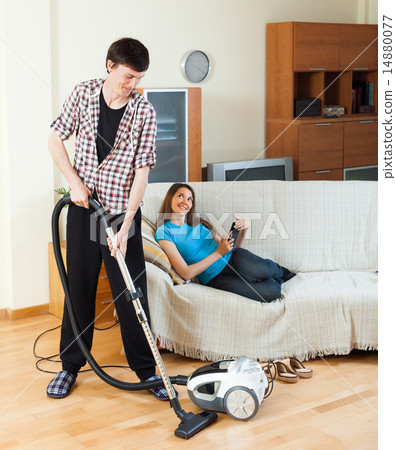 Man cleaning while woman lying with laptop 14880077