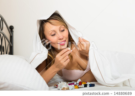Female eating sweets in bed 14880689