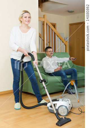 Wife hoovering room, husband relaxing Wife hoovering room, husband relaxing 14880862