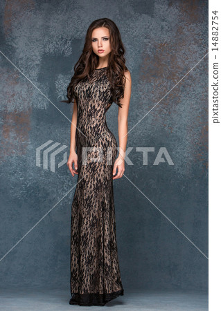 Beautiful young brunette woman with her hair posing in a i long dress. Studio, on gray background Beautiful young brunette woman with her hair posing in a i long dress. Studio, on gray background 14882754