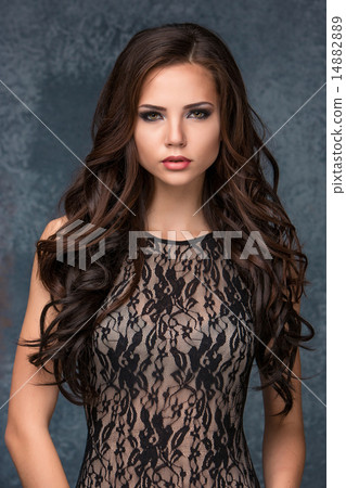 Beautiful young brunette woman with her hair posing in a tracery dress. Studio, on gray background Beautiful young brunette woman with her hair posing in a tracery dress. Studio, on gray background 14882889