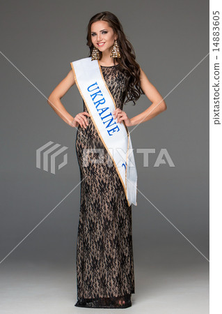 Beautiful young brunette woman with her hair posing in a i long dress. Studio, on gray background 14883605