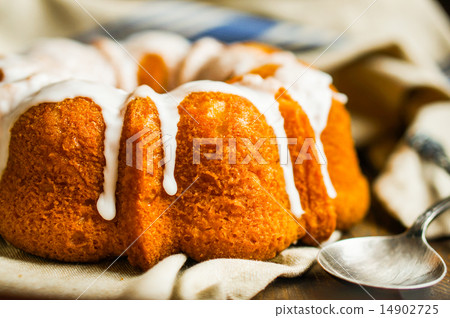 Bundt cake with white glaze on rustic background Bundt cake with white glaze on rustic background 14902725