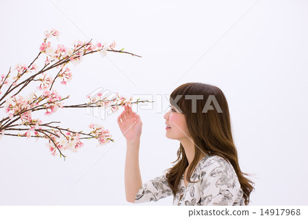 A young woman with a smile holding a cherry branch in her hand A young woman with a smile holding a cherry branch in her hand 14917968