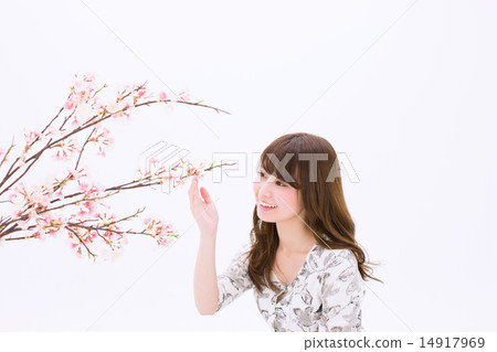 A young woman with a smile holding a cherry branch in her hand A young woman with a smile holding a cherry branch in her hand 14917969