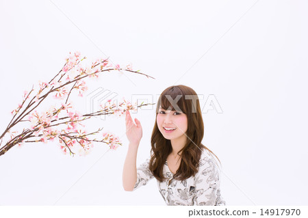 A young woman with a smile holding a cherry branch in her hand 14917970