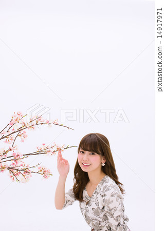 A young woman with a smile holding a cherry branch in her hand 14917971