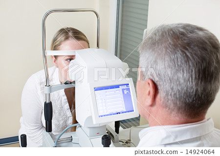 Young woman having her eyes examined by an eye handsome elderly doctor 14924064