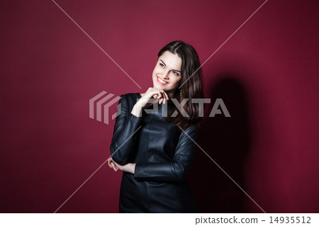 Portrait of young beautiful woman in leather dress on red background Portrait of young beautiful woman in leather dress on red background 14935512