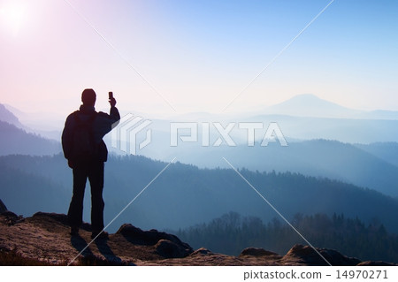 Hiker is taking selfie on the peak at sunrise Hiker is taking selfie on the peak at sunrise 14970271