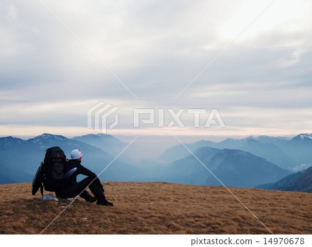 Tired tourist with backpack sit on stone in meadow 14970678