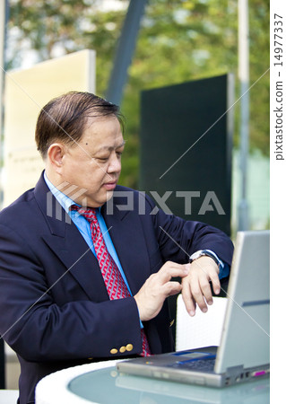 Asian businessman looking at watch 14977337