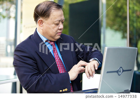 Asian businessman looking at watch 14977338