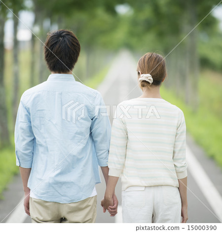 The back of a couple holding hands in one road 15000390