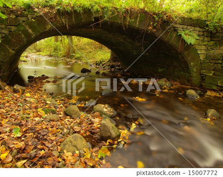 Old stony bridge above autumn river. Clear water 15007772