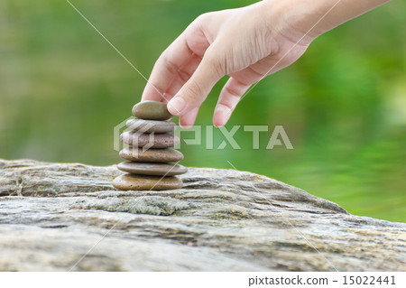 Hand put stone building a pile of zen stones Hand put stone building a pile of zen stones 15022441
