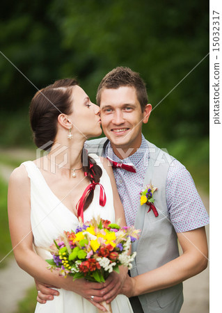 happy couple standing in green park, kissing 15032317
