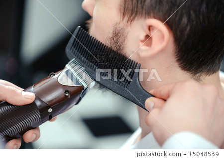 Man shaves his beard with a hair clipper Man shaves his beard with a hair clipper 15038539