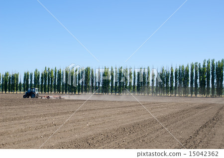 tractor on black ploughed field under blue sky tractor on black ploughed field under blue sky 15042362