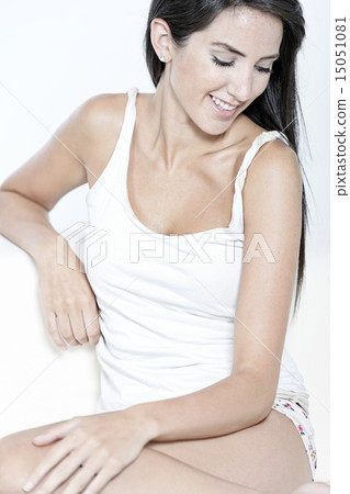 Woman in white vest top sitting on sofa 15051081