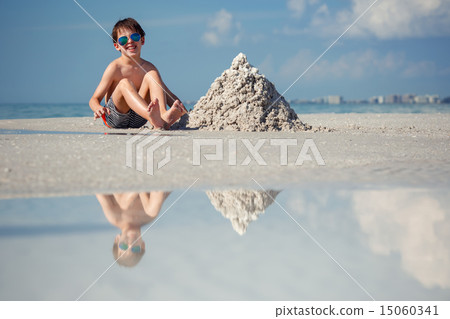 Cute little son building sand castle at beach 15060341