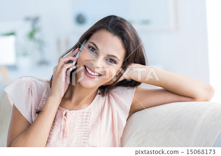 Smiling beautiful brunette relaxing on the couch and speaking on Smiling beautiful brunette relaxing on the couch and speaking on 15068173