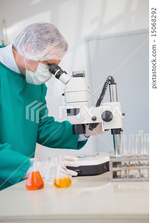 Scientist in scrubs using microscope 15068292
