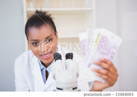 Smiling scientist holding money and looking at camera 15069005