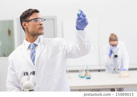 Scientist examining blue precipitate in tube 15069015