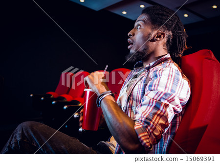 Young man watching a film and drinking soda 15069391
