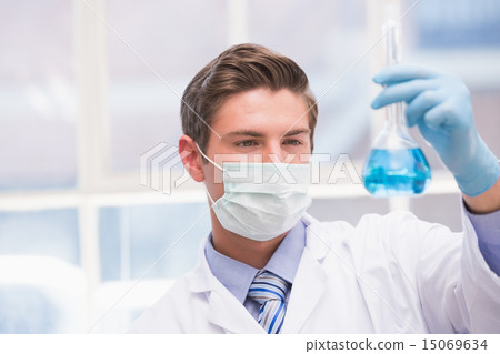 Scientist examining beaker with blue fluid Scientist examining beaker with blue fluid 15069634