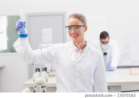 Scientist examining blue precipitate in baker 15070163
