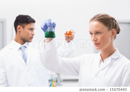 Concentrated scientists holding beakers with fluid 15070493