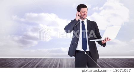 Composite image of businessman talking on phone holding laptop 15071097